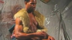 Black gladiator stud sits on his chair and chokes the life out of his prick